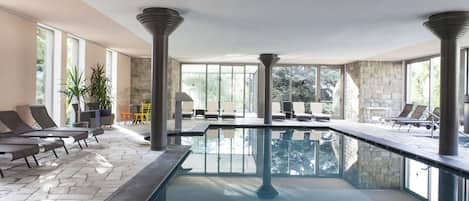 Una piscina cubierta, una piscina al aire libre, tumbonas