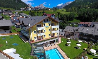 Hotel a più piani con piscina e area salotto esterna, immerso in un paesaggio montuoso.