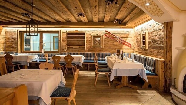 Un intérieur rustique avec des murs, des tables et des bancs en bois, disposés pour les repas.