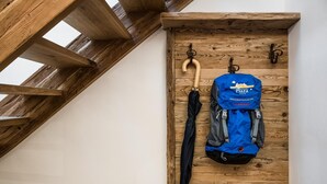 Un mur en bois avec un sac à dos bleu et un parapluie suspendus à des crochets.