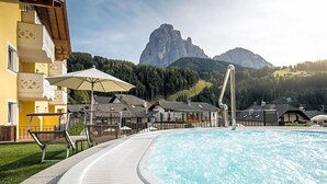 Une piscine avec une vue sur les montagnes, des espaces de détente en plein air et un bâtiment doté de balcons.