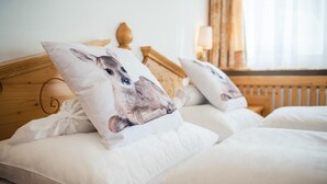 Une chambre d’hôtel avec deux lits, chacun doté de draps blancs et d’un oreiller orné d’un motif de cerf.