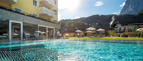 Un hotel con piscina, mobiliario exterior y vistas a la montaña.