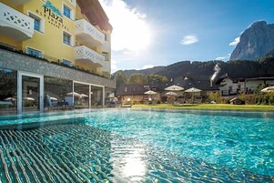 Un hotel con piscina, area salotto all'aperto e vista sulle montagne.