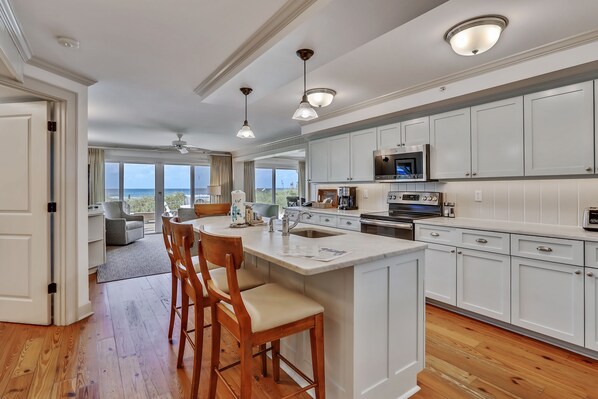 A spacious kitchen with white cabinetry, a large island, and a view to the outdoors.