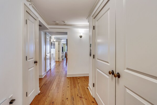 A hallway with white doors and wooden flooring.