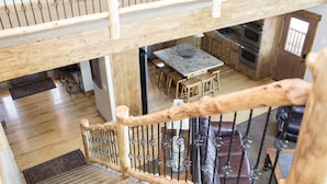 Un escalier en bois, doté d’une rampe, mène à un espace repas comprenant une table et des chaises.