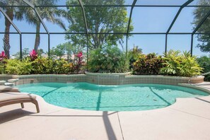 Ein Pool mit klarem Wasser, umgeben von tropischen Pflanzen und Palmen.