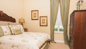 A bedroom with a bed, a nightstand, a lamp, a dresser, and two framed pictures on the wall. - Players Club Membership Available With Heated Pool (Naples)