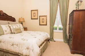 Un dormitorio con cama, mesita de noche, lámpara, cómoda y dos cuadros en la pared.