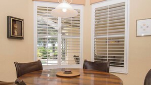A dining area with a round table, four chairs, and a pendant light. - Players Club Membership Available With Heated Pool (Naples)