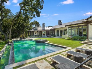 A modern house with a swimming pool, outdoor seating, and a well-maintained lawn.