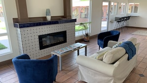 Ein Wohnzimmer mit Kamin, blauen Sesseln, einer Couch und einem Couchtisch.