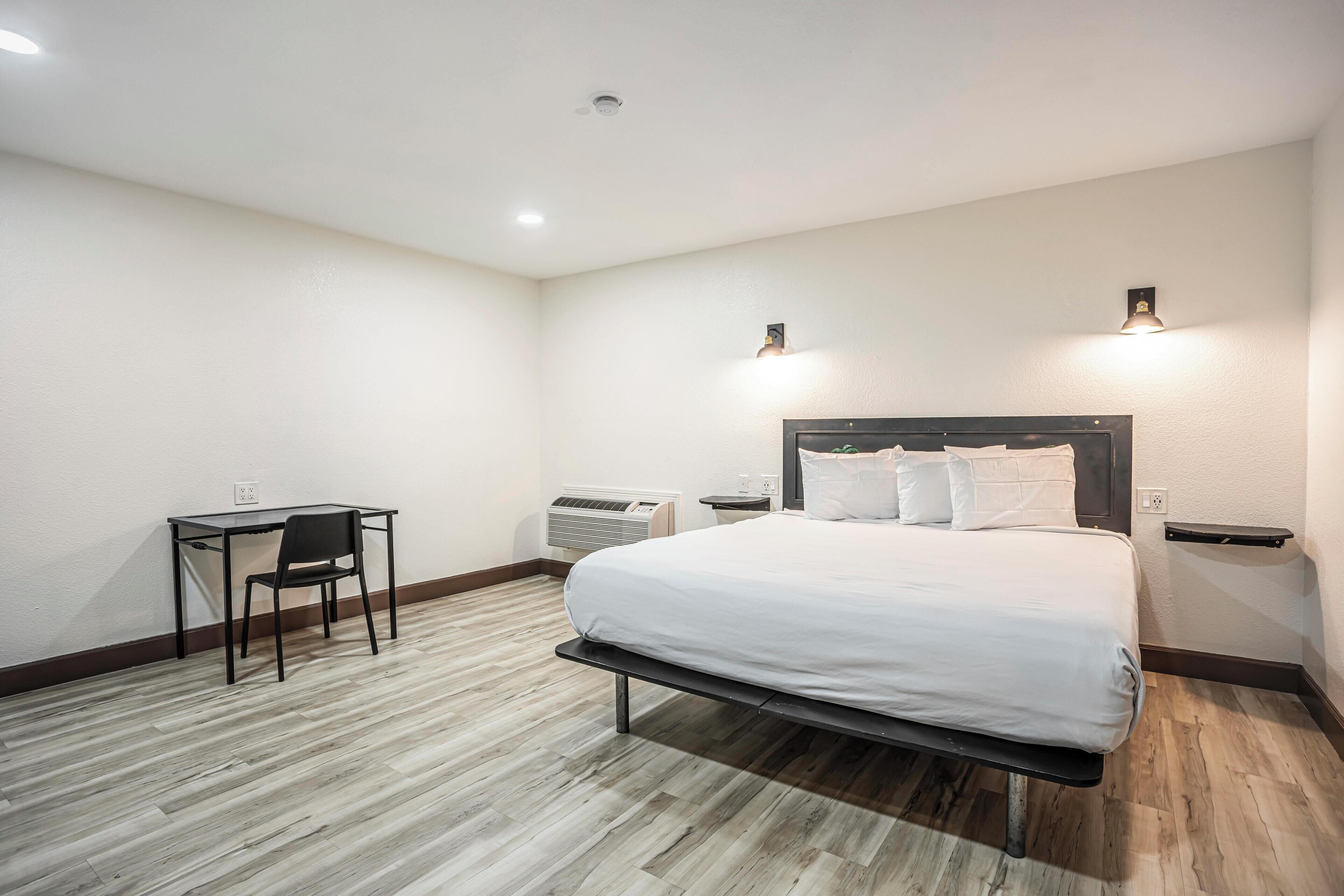 A hotel room with a bed, a desk, and a chair.
