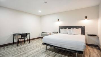 Hotellihuone, jossa on sänky, työpöytä ja tuoli.