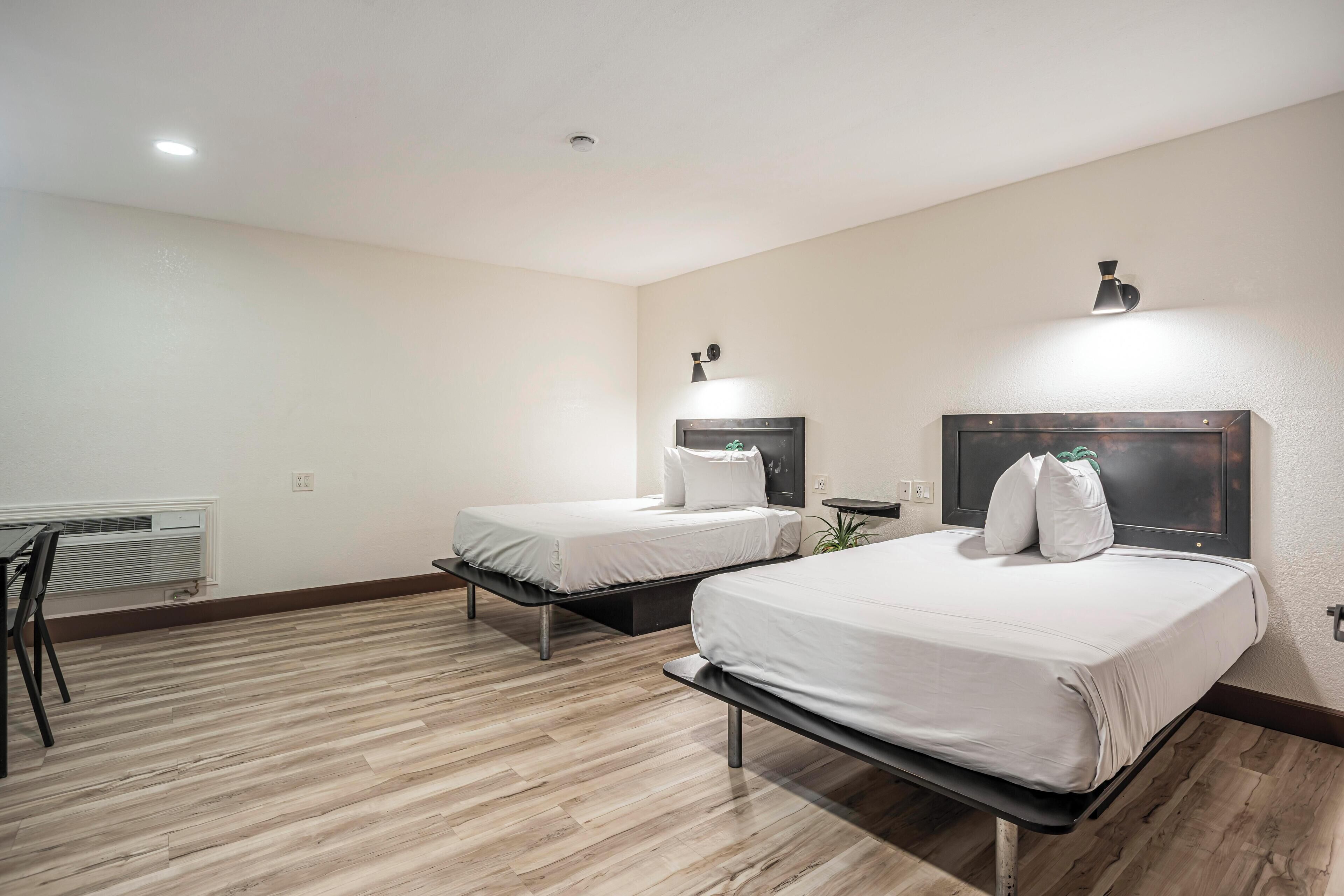 Ein Hotelzimmer mit zwei Betten, einem Schreibtisch und einem Stuhl.