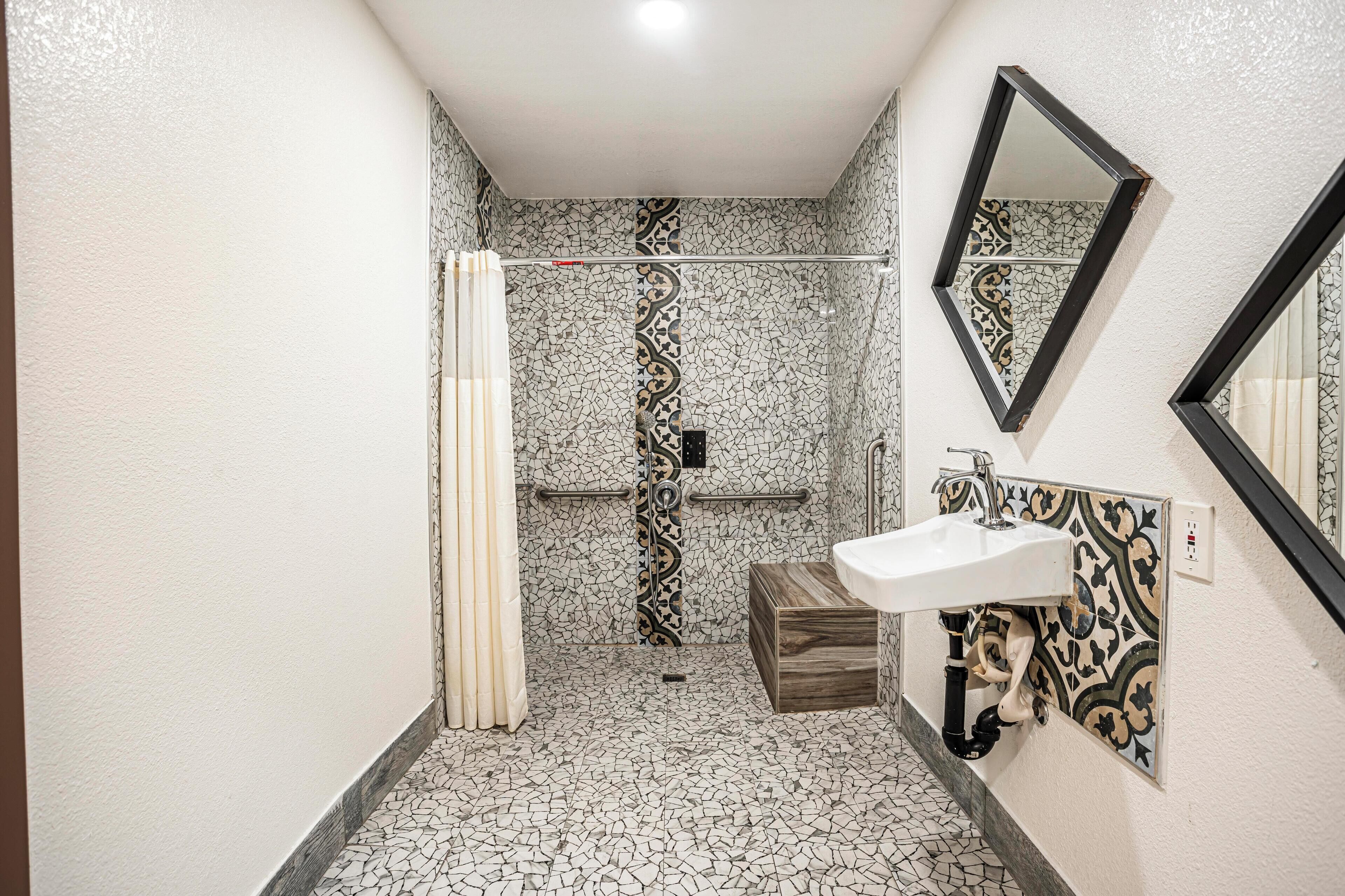 Un baño con ducha, lavabo y espejo.