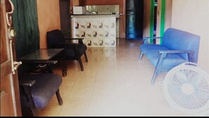 A room with a dining table, two chairs, a blue sofa, a white fan, a tiled backsplash, and a refrigerator. - Hermosa Quinta en Costa Pájaros (Manzanillo)