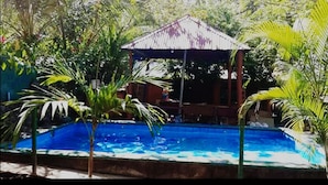 A swimming pool with a gazebo structure in the background surrounded by tropical vegetation. - Hermosa Quinta en Costa Pájaros (Manzanillo)