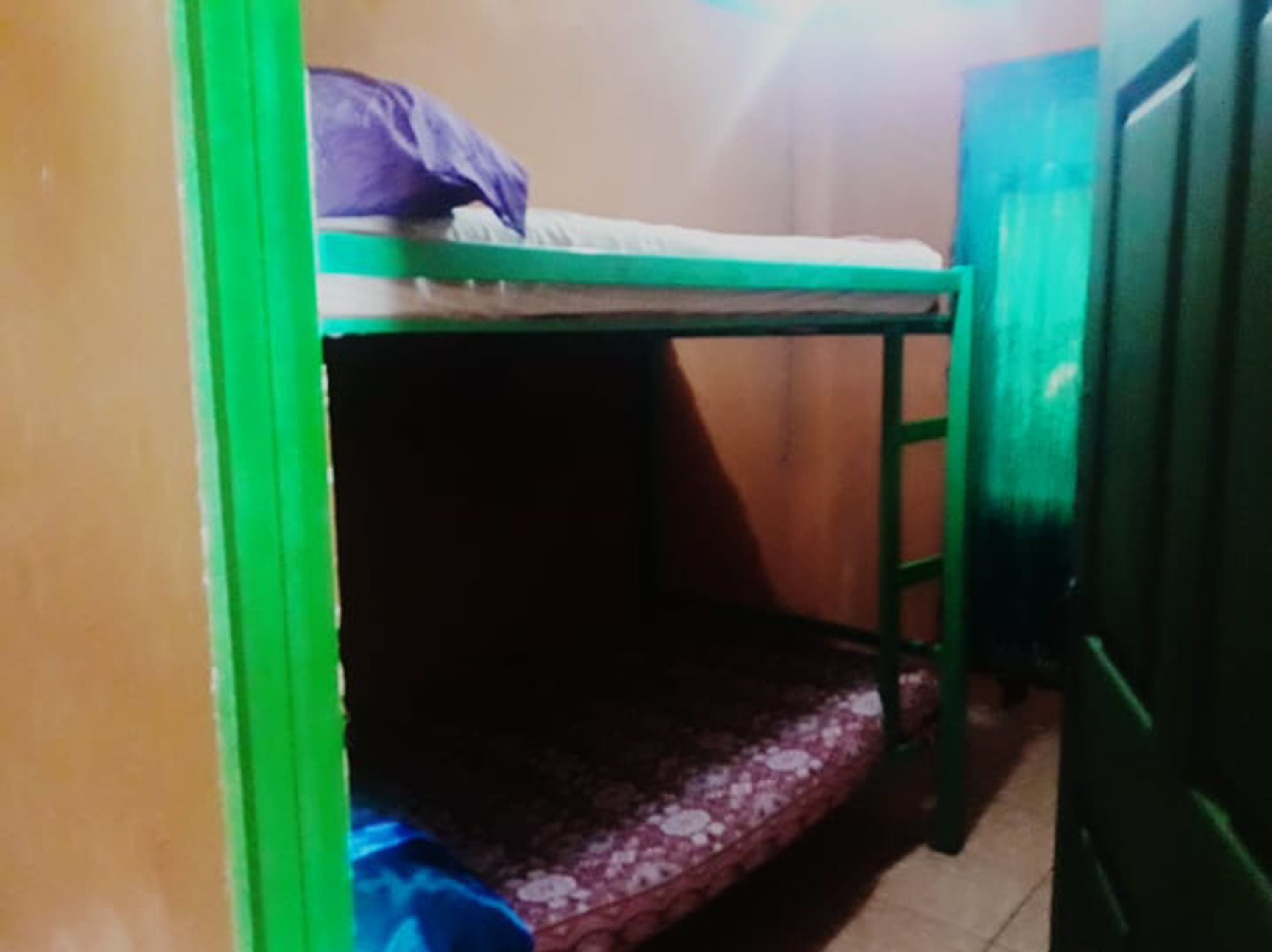 A bunk bed with a green frame and a mattress on top.