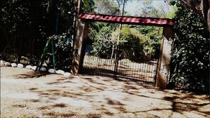 A gated area with a metal fence, surrounded by trees and a gravel path. - Hermosa Quinta en Costa Pájaros (Manzanillo)