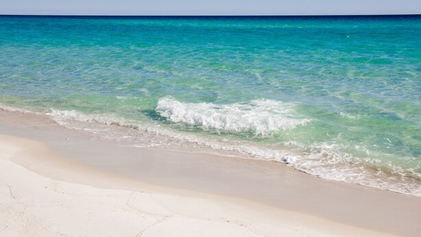 Una platja amb aigua turquesa transparent i sorra blanca.