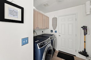 A laundry room with a washing machine, dryer, and a vacuum cleaner.