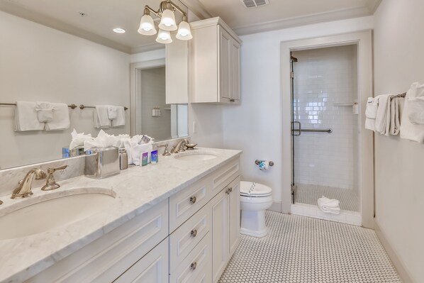 A bathroom with two sinks, a large mirror, a toilet, and a shower area.