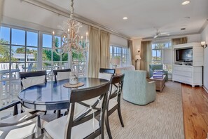 Een moderne hotelkamer met een eethoek, een zithoek en een balkon met uitzicht op palmbomen.