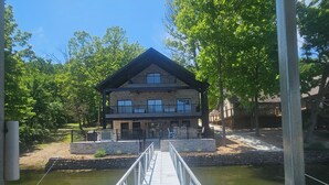 A wooden bridge leading to a two-story lodge with a stone facade and balconies. - COMPLETELY REMODLED!! Gorgeous 5 BR/5.5 BA in NO WAKE cove, Dock w/12'x30' slip (Sunrise Beach)