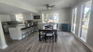A spacious kitchen with white cabinets, a dining area with a wooden table and chairs, and large windows providing natural light. - COMPLETELY REMODLED!! Gorgeous 5 BR/5.5 BA in NO WAKE cove, Dock w/12'x30' slip (Sunrise Beach)