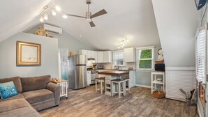 Une cuisine moderne dotée d’un îlot central, de meubles blancs et d’un ventilateur de plafond.