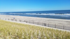Une plage avec une clôture en bois et de l’herbe au premier plan.