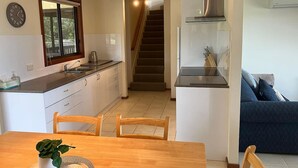 Een kleine keuken met een eethoek, een trap en een woonkamer met een bank.