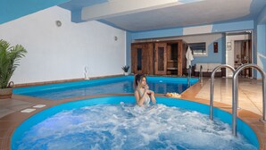 Ein Wellnessbereich mit Whirlpool, Holzschrank und Topfpflanze.