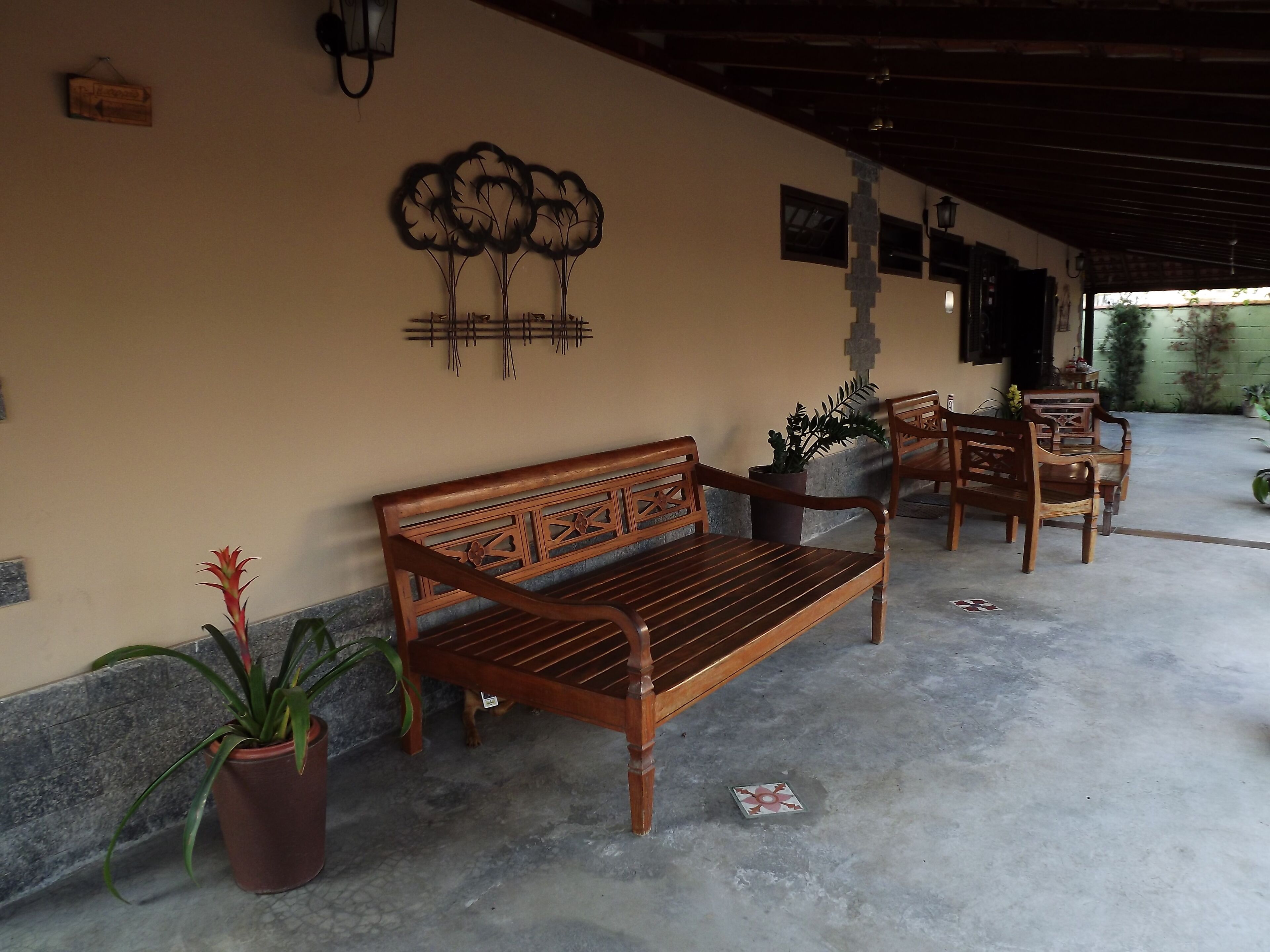 A wooden bench with intricate carvings, a potted plant, and a wall-mounted decorative piece.