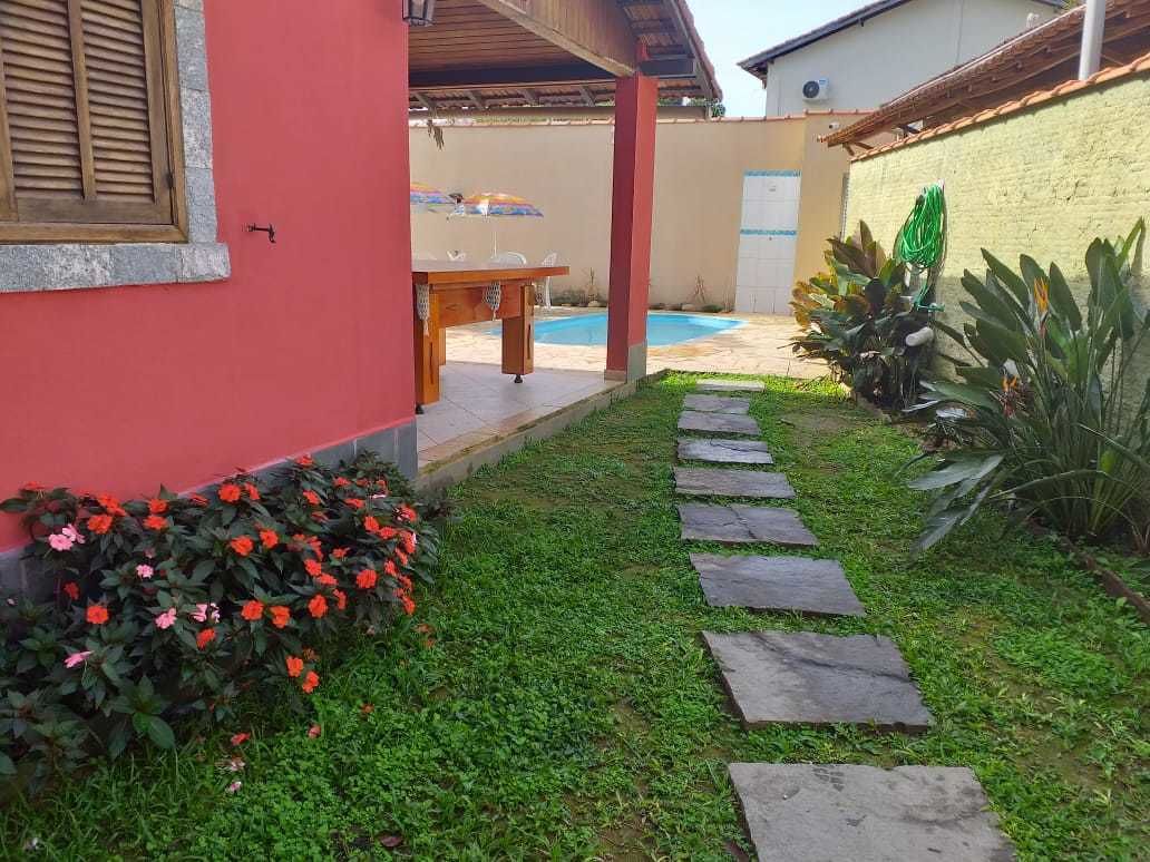 A garden with a stone path leading to a pool area, surrounded by a red building and a yellow wall.