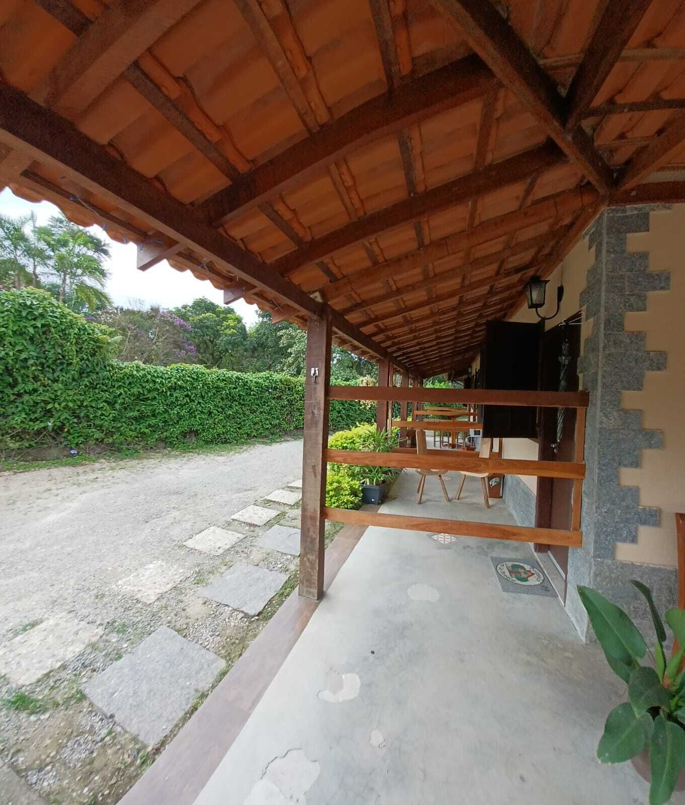Un espacio de estar al aire libre techado con suelo de hormigón, vigas de madera y pared de piedra.