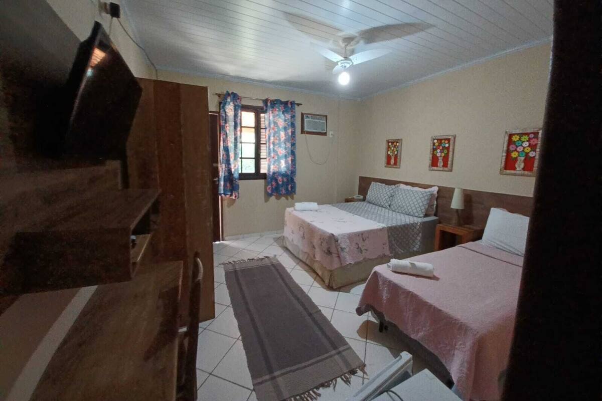 Quarto com duas camas, ventoinha no teto e decoração floral nas paredes.