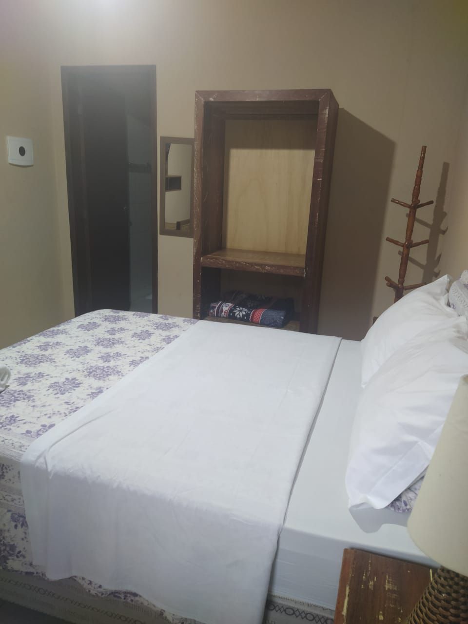 A room with a bed, a wooden cabinet, and a door.