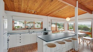 Een moderne keuken met een groot eiland, witte kasten en uitzicht op de wijk.