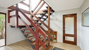 Een spiraaltrap met houten treden en metalen leuningen in een kamer met witte bakstenen muren en een houten vloer.