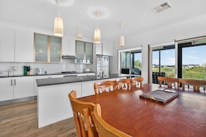 A modern kitchen with white cabinets, a wooden dining table, and pendant lights. - 35 Blanche Parade, Hindmarsh Island (Hindmarsh Island)