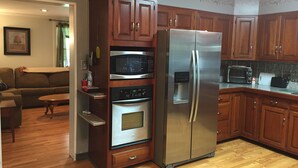 A kitchen with wooden cabinets, a stainless steel refrigerator, a microwave, and an oven. - Beautiful Family Home Along Fish-friendly Manada Creek (Hummelstown)