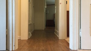 A hallway with wooden flooring and white walls, leading to a room with a door. - Beautiful Family Home Along Fish-friendly Manada Creek (Hummelstown)