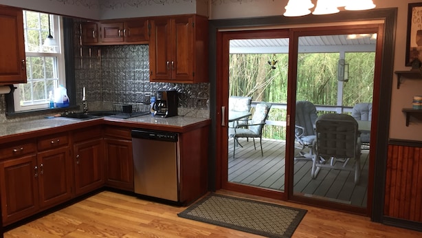 A kitchen with wooden cabinets, a dishwasher, a coffee maker, and a window. - Beautiful Family Home Along Fish-friendly Manada Creek (Hummelstown)