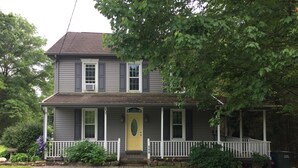 A two-story house with a front porch, a yellow door, and a small front yard. - Beautiful Family Home Along Fish-friendly Manada Creek (Hummelstown)