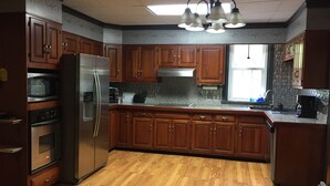A kitchen with wooden cabinets, a stainless steel refrigerator, a microwave, a toaster, and a sink. - Beautiful Family Home Along Fish-friendly Manada Creek (Hummelstown)