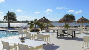 A poolside area with lounge chairs, tables, and umbrellas, overlooking a body of water. - Spacious Gold Coast Townhouse in lush community close to beaches (Noord)