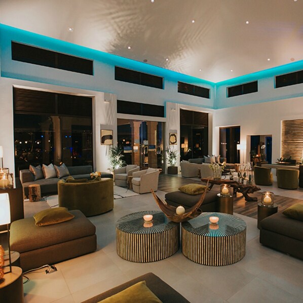 A spacious living area with multiple seating options, large windows, and a modern design.